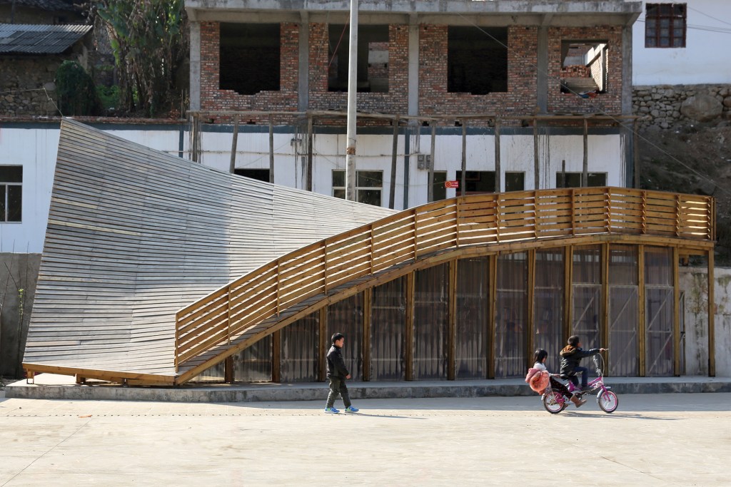 The multi-purpose curved gable roof of the Pinch serves as an pedestrian ramp between the village's main elevation and a newly developed plaza.
