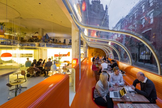The bright orange color of the storefront café helps identify Second Home to passersby. Mirrored acrylic delineates the floor plate and reflects distorted views of the outdoors.