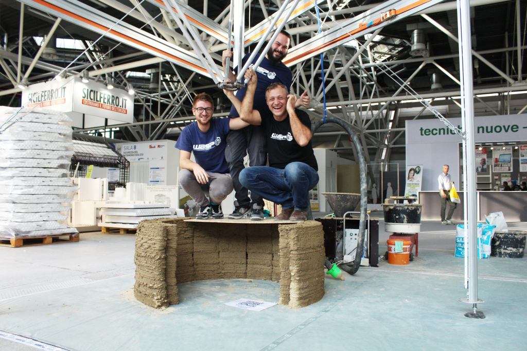Members of Italian firm WASP are supported by a clay structure printed using their 13.1-foot-tall commercial 3D printer.