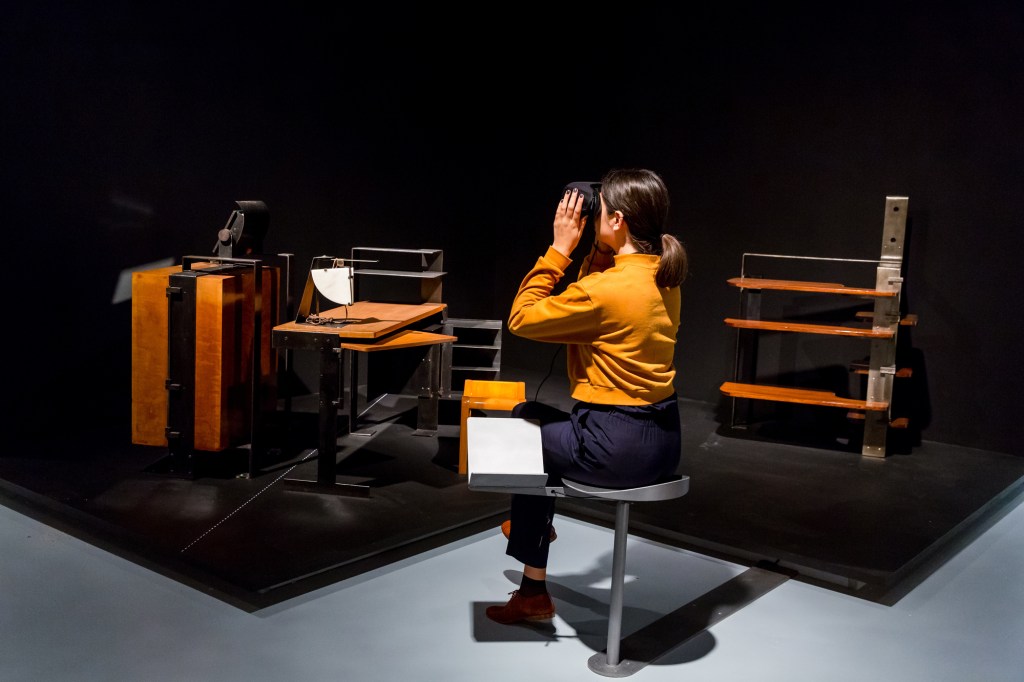 A visitor to the exhibition wears virtual reality goggles that offer a 3D experience of Chareau's furniture in its original context