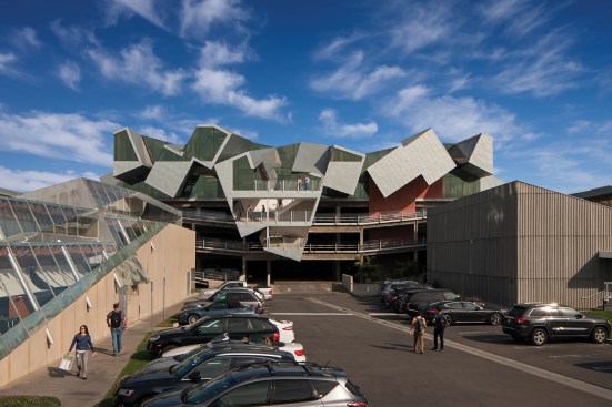 Pterodactyl's western facade overlooks a parking lot framed by four other Eric Owen Moss projects: The Umbrella (at right), Slash (at left) and Backslash, and Stealth. The new office and exterior stair projects out and over an existing parking garage.