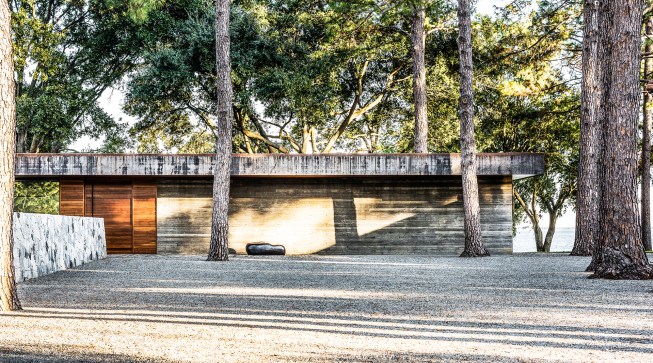 Raw 14-inch-thick concrete, used throughout the house’s interior and exterior, forms part of the entry façade. The overhanging flat roof is wrapped with rusting carbon steel.