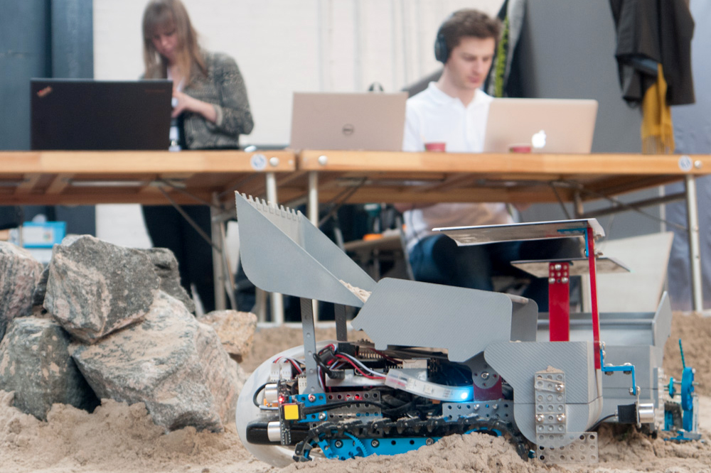 An autonomous robot from the MARS cluster rolls across the sandpit while researchers develop new logic for its movements.