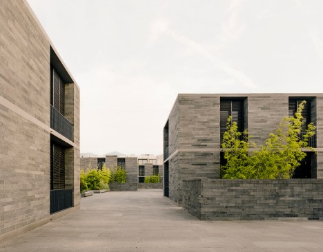 The concrete-framed houses are organized around four small plazas, such as the one shown, that are connected via pedestrian walkways.