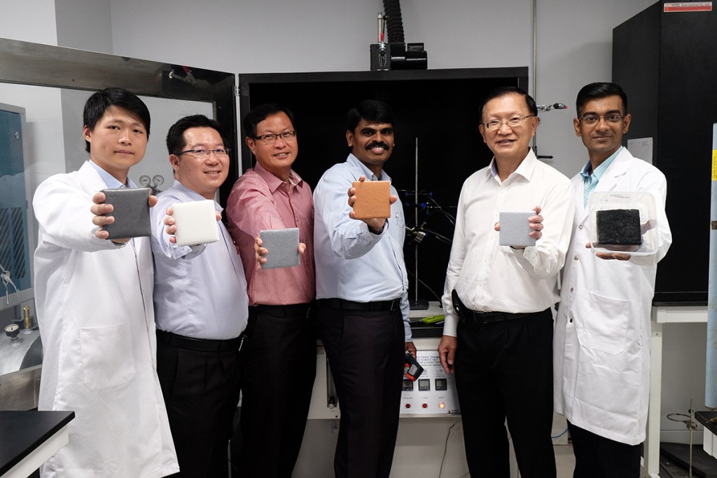 The research team holding steel plates coated with FiroShield of different colors.