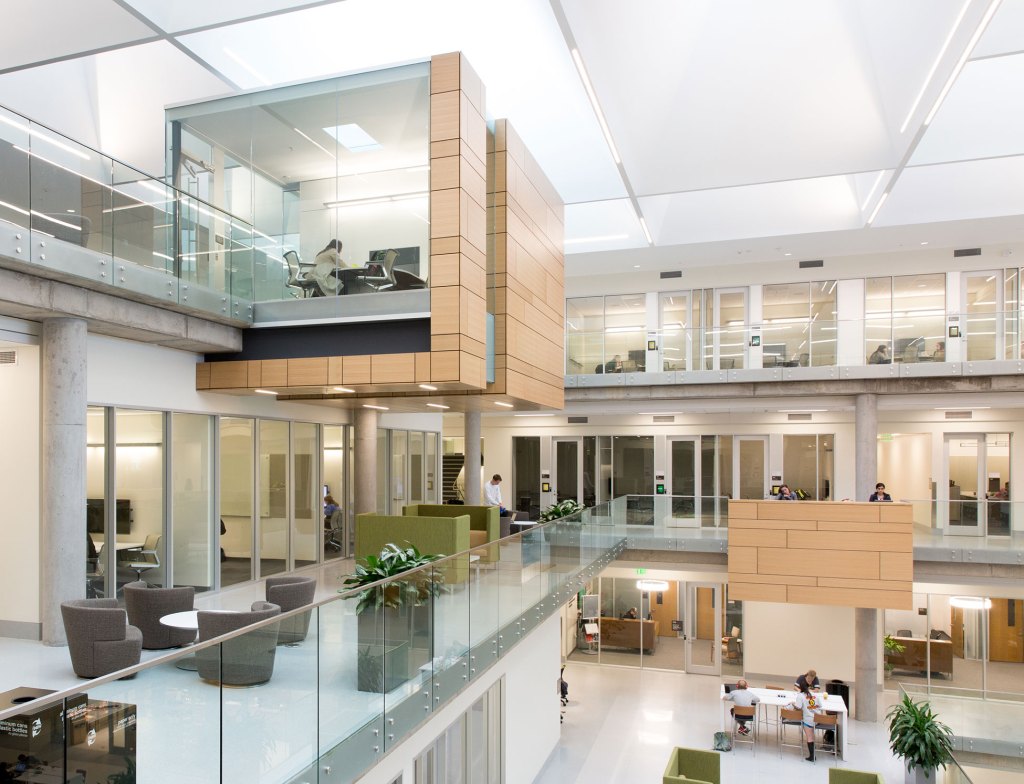 Cantilevered team workrooms and projecting counter areas, both clad in light wood, act as vertical reflectors of daylight that filters down from the deep skylight wells above.