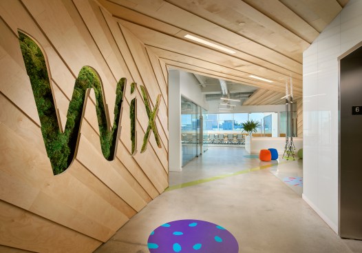 A living wall at the entrance made of green moss. displays the Wix logo