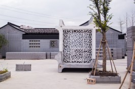 Located on the grounds of the WinSun architectural 3D printing facility in Suzhou, China, this 3D-printed concrete guardhouse prototype integrates furniture, shelving, seating, and even a bed.