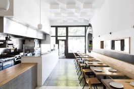 Repeating archways and sun motifs create continuity between juxtaposed dark and light seating areas of a Taiwanese soul food restaurant in the Mar Vista neighborhood of Los Angeles.