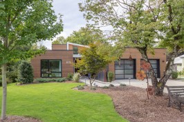 A single-story form faces the street, set back on the lot as deeply as  neighboring houses.