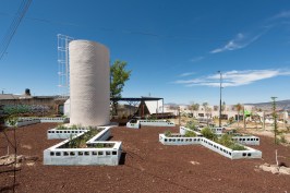 Garden with water tower at the Apan Housing Laboratory in Apan, Mexico. Welcome and education center can be seen beyond at right.