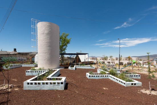Garden with water tower at the Apan Housing Laboratory in Apan, Mexico. Welcome and education center can be seen beyond at right.