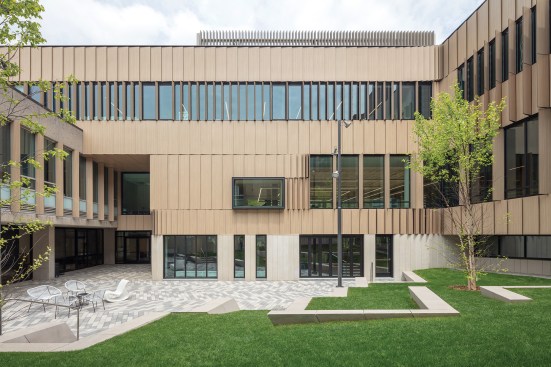 An existing central courtyard (now enclosed by the new addition) is lined in a rainscreen clad in wood-grained FunderMax phenolic panels. The panels were oriented to minimize solar gain, and to signal the pattern of movement along the programmed interior ramps.