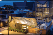 Rabbit Hole Distillery at night. The serrated, two-direction sign above the main entrance captivates passersby. The Manufacturing Atrium glows like a lantern in the cityscape.