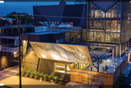 Rabbit Hole Distillery at night. The serrated, two-direction sign above the main entrance captivates passersby. The Manufacturing Atrium glows like a lantern in the cityscape.