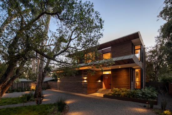 At the front of the home, one is greeted by the California live oak and Eucalyptus trees that define the local landscape and keep in proportion with the generous home, while the airplane hangar style garage door, finished with charred siding, “disappears” when closed.
