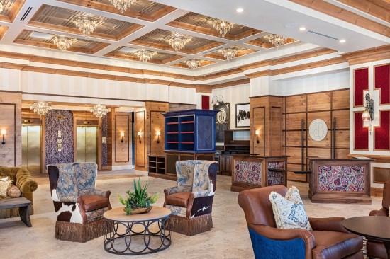 The Lobby of the Brownwood Hotel, in The Villages, FL, mixes rustic cowboy-inspired elements with an elegant coffered ceiling and crystal chandeliers.