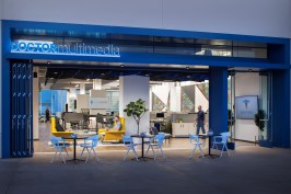 The inviting ground floor entrance features a public-facing glass door and large sliding windows, while the café tables and lounge chairs encourage community seating