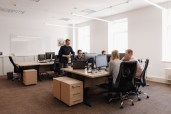 Full concentration at work. Group of young business people working and communicating while sitting at the office desk together with colleagues sitting in the background