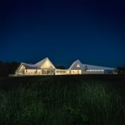 A series of barn roofs connect and contort to cover the program. The building overlooks the 'Hillside Meadow'