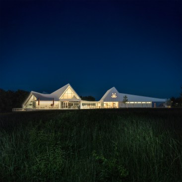 A series of barn roofs connect and contort to cover the program. The building overlooks the 'Hillside Meadow'