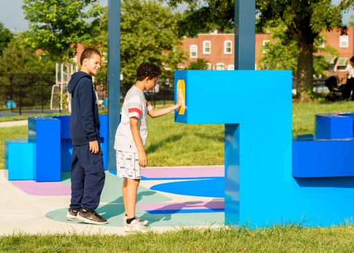 Two local kids from the community who helped design the space play with the installation.