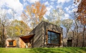 Rustic yet refined facade materials seamlessly meld into the surrounding environment, while stained Atlantic white cedar cladding gives the house a dramatic, monolithic expression.