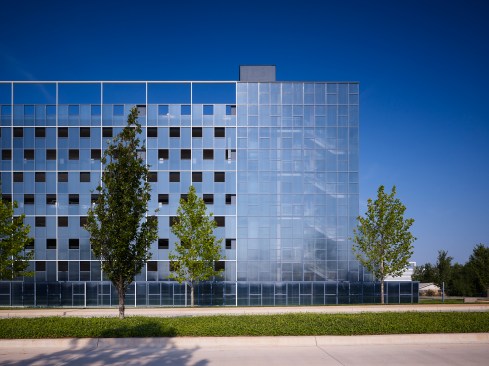 East elevation illustrating the primary entrance on the left, the transparent stair lanterns and the 25% open façade all set in the square grid bris soleil