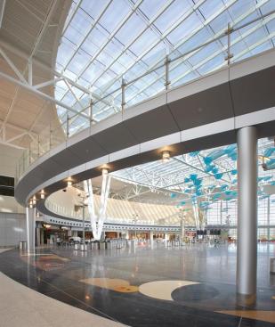 Topped by a 230-foot-diameter skylight, the civic plaza is a central space where visitors can pass time at the airport before going through security. It is heated and cooled by a radiant floor system that limits the amount of energy needed to keep the users comfortable in the vast space. HOK expects the natural convection system to save 21 percent more energy than dictated by ASHRAE standards.  Skylight Supersky Insulated skylights supersky.com  Lighting Syska Hennessey Group Civic plaza lighting syska.com  Lighting Hess America Pole lights in civic plaza hessamerica.com  Handrails Livers Bronze Co. Custom glass railings  liversbronze.com