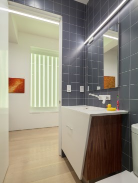 Previously, a window of frosted glass block punctuated the hallway. Unfortunately, it overlooked a perpetually dark courtyard and illuminated nothing. I changed this into an art installation of light. With its multiple settings, one can rotate through a selection of colors to wash the space in colored light, instantly changing the mood and feel of the space. The portal is seen here in lime green.