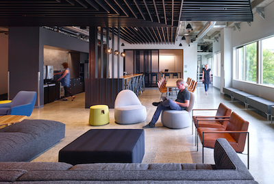 Open workspaces contain living room setups with sofas, lounge chairs and large TVs for game testing.