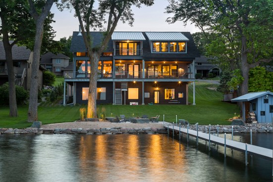 Back exterior of split level lake home showing lake and multiple levels and balconies