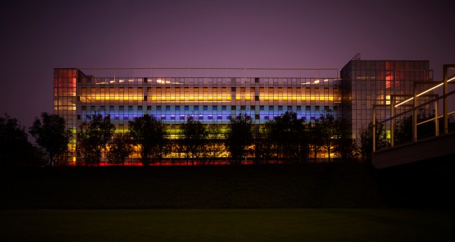 Night time view from CHK 14 to Car Park 3.  Conceived as companion structures, the light box provides open and secure access for staff