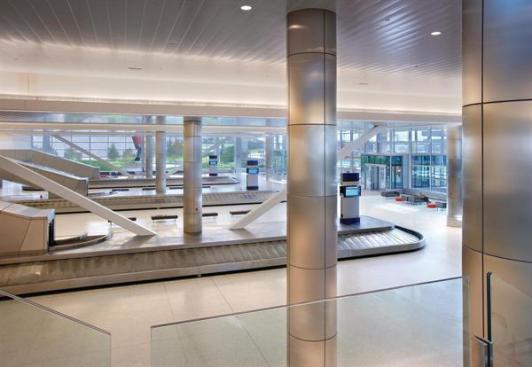 The baggage claim area is located on the lower level of the two-story main volume, underneath the ticketing hall. The space is bordered on three sides by glass, allowing daylight to permeate the space, and offering views to adjacent landscaped areas.  Downlights Edison Price Lighting Compact fluorescent and ceramic metal halide downlights epl.com  Ceilings Perry Acoustics Co. Public area metal ceilings