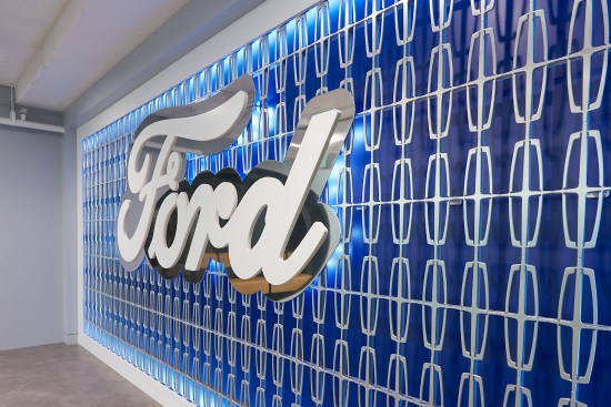 Ford’s office pays homage to Ford Motor Company and Lincoln Motor Company’s iconic branding with the entrance’s 3-D, Ford-blue feature wall. The custom edge LED lit millwork wall by K. Mack Enterprises showcases a floating aluminum, satin-finish Ford logo anchored in an interlocked Lincoln-logo mesh grid. The polished aluminum behind the white lacquered logo draws attention to the wall.