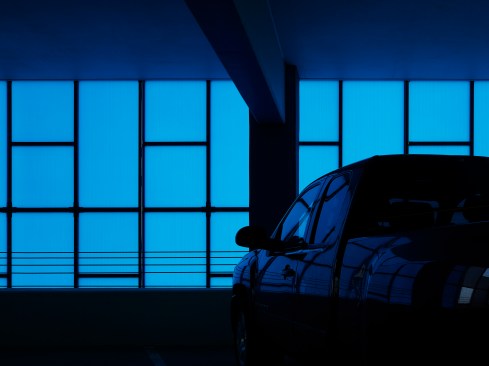 Blue light spills over a black truck.  