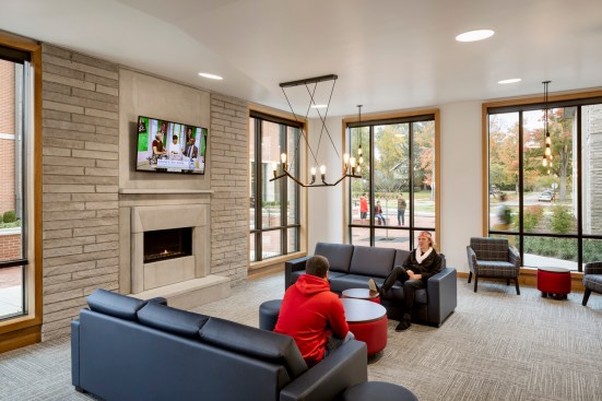 Students enjoy watching TV and hanging out in the common area of the Student Life halls while surrounded by the warm materials and large windows that enclose the living room. 