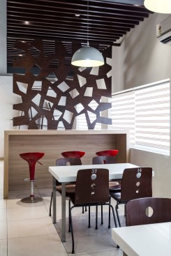A high table with red bar stools adds a splash of colour to the warm toned interiors.