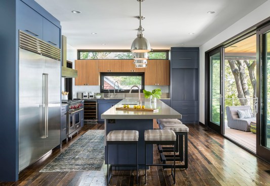 Modern kitchen with reclaimed wood floors, blue cabinets and large sliding door to outside deck