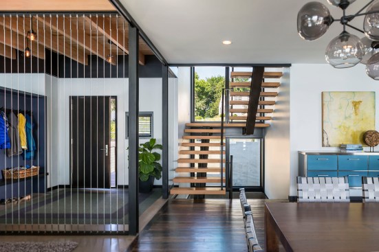 Front entryway of house showing part of dining area and modern open stairs