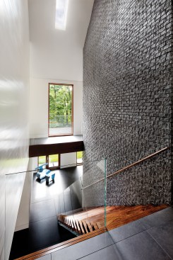 The house’s central stair connecting the lower-level guest bedrooms to the main living spaces runs behind the north fireplace.