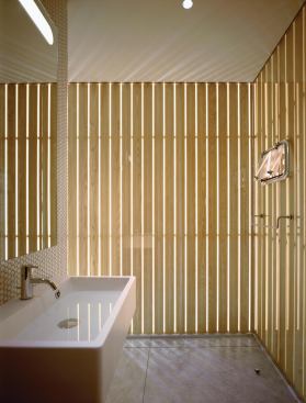 In the Cooper Square bath, light bounces through the offset slats of wood-and-glass skin.