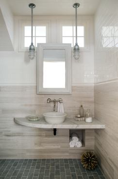 To accommodate a wheelchair in this small first-floor bathroom, the designers took a "wet room" approach, turning the whole room into a shower. The transom windows bring in outside light through the wrap-around stairwell. The countertop is made with a piece of remnant marble.