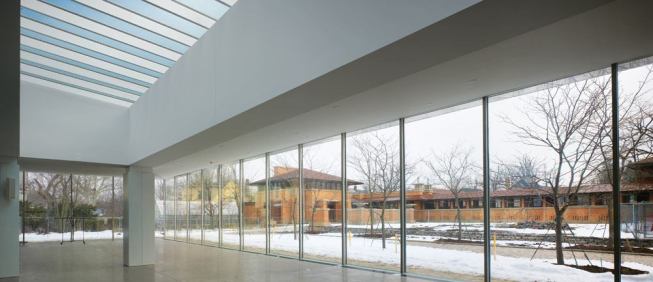 Marking the perimeter of the space are thin 2 3/4" stainless steel columns, engineering by Skidmore, Owings & Merrill that can help carry the load of the roof and support the region's heavy snow loads. Far from encouraging the snow to run off, the inverted slope of the roof retains the snow which acts as an insulator to help offset heat loss through the glazing. The columns are so thin that, although they support the roof, they do not disrupt the view. And working in dialogue with Wright's complex, the columns are spaced the same distance apart as the columns on the pergola.