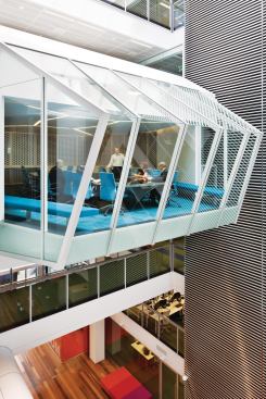 Not technically a pod, the Skybox is a formal conference room that bridges the two sides of the atrium on the fourth floor. With an articulated glass skin that nods to the angled skylight above, the room features bright turquoise furniture and finishes. Wilkinson's team worked with furniture manufacturers to create a custom conference table with inset monitors to facilitate high-tech teleconferencing and presentation options.