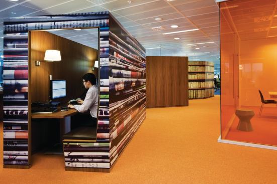 Each communal plaza has a series of private workspace options, such as these semi-enclosed touchdown spaces. Employees are free to use them to accomplish specific tasks, but the next day they may find themselves working in a more loungelike collaborative pod. Supergraphics and color delineate the plazas, which serve as destinations throughout the building.