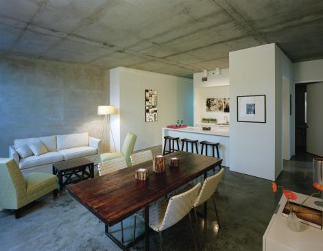 Inside, the apartments have simple, loftlike floor plans that afford city views from the living spaces and bedrooms. Finishes are spare, consisting of gypsum walls, polished concrete floors, and sliding polycarbonate panels that divide the rooms. About two-thirds of the apartments are one-bedroom units; the others have two bedrooms.