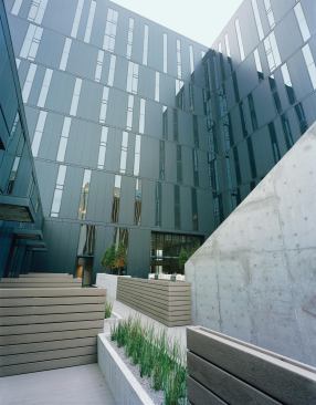 Private outdoor space for the two-story townhouses opens out onto the pool deck but is kept separate from public circulation areas by plank fences and tall planters. The view up to the L-shaped residential tower shows the variegated façade: On these habitable levels, there are more glass panels per floor than on the parking levels below. This is in order to admit light into, and city views out of, the apartments.