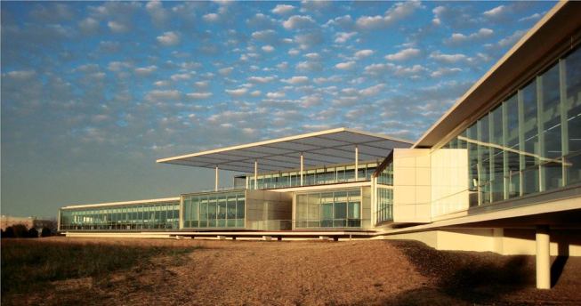 The building's S shape and ample glazing mean that not only do employees get views of the wetlands, they can also see into other parts of the workspace, creating a visual sense of community throughout the long, thin building. At the center of the structure, a roof deck—connected to a second-story employee lunch room—is covered with a metal-grate awning that provides some shading and contributes to the building's horizontal aesthetic.