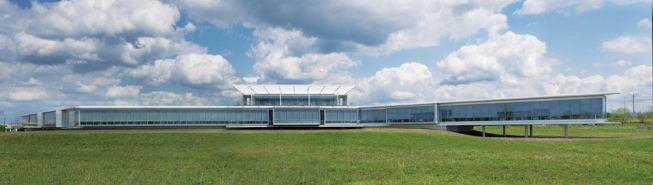 The west façade, facing a wetlands area, is almost entirely glass, maximizing daylight inside and views out. The horizontality of the structure is emphasized by what Metter refers to as 'brows,' thin concrete projections that run along the top and bottom of the single-story main building and cantilever beyond the end of the window wall.